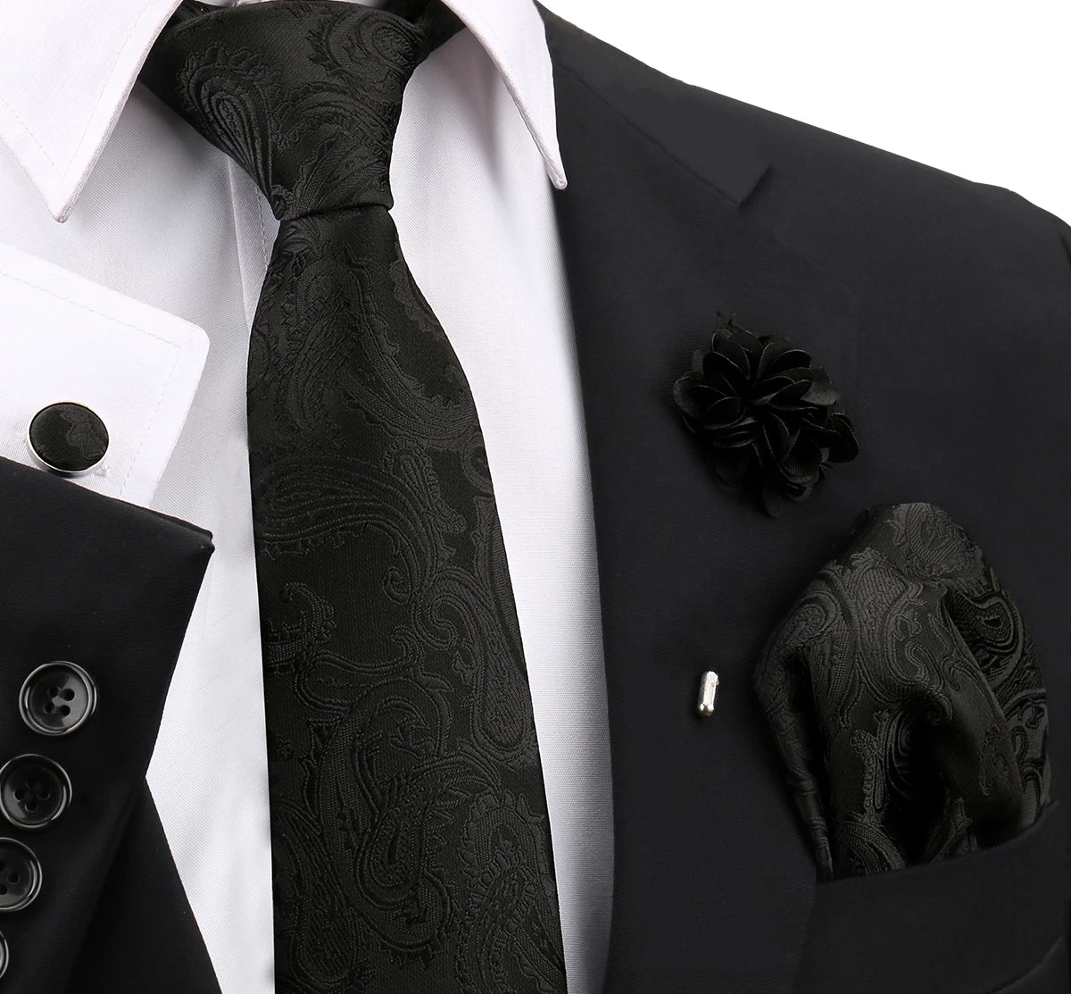 Schwarzes gemustertes Krawatt wird vor einem weißen Hemd und einer schwarzen Jacke präsentiert mit Accessoires.