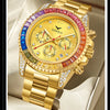 A gold quartz watch with a pink and blue bezel and diamond accents resting on a light-colored surface.