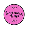 Pink enamel pin featuring the text Professional Yapper in black lettering.