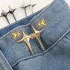A pair of gold star-shaped decorative buttons are shown against a blue denim fabric.