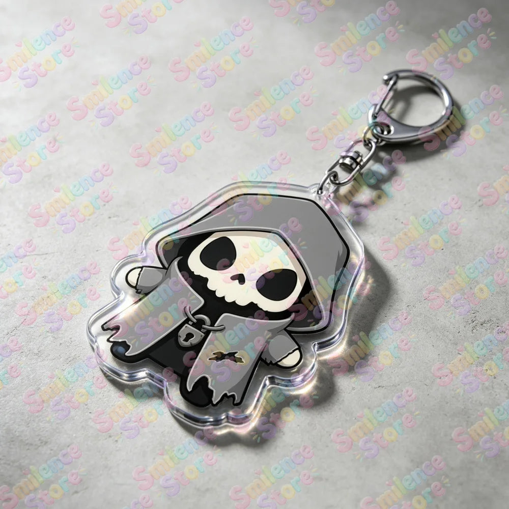 A clear acrylic keychain featuring a skull and crossbones design with a hood and a silver keyring.