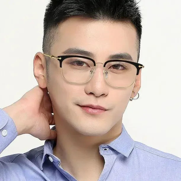 A young man wearing black half-frame reading glasses and a light blue collared shirt.