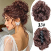 A woman shows off a voluminous curly messy bun hairstyle secured with a claw clip hair accessory.
