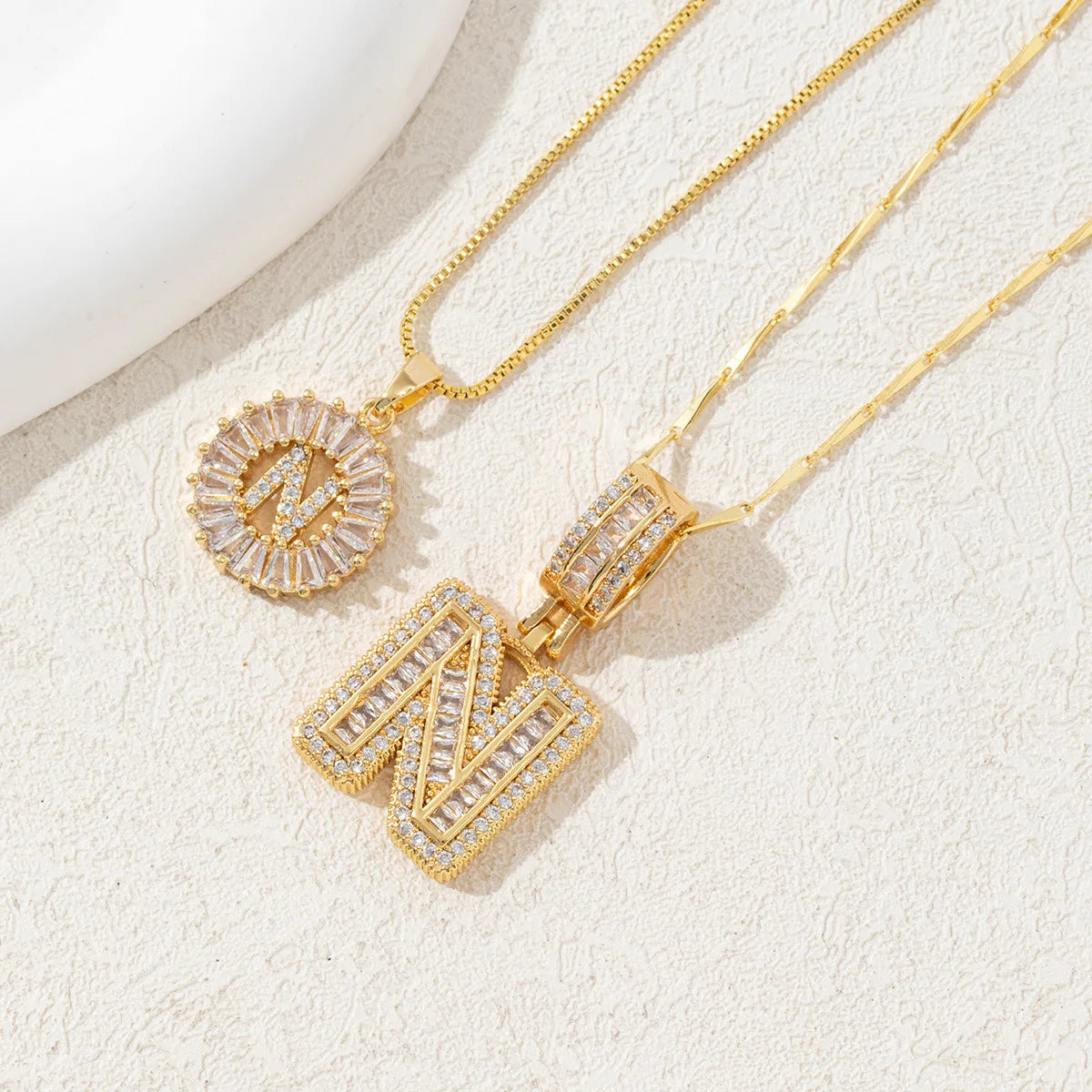 Gold-toned necklace set featuring CZ crystal pendants shaped like the letter N and an initial circle.