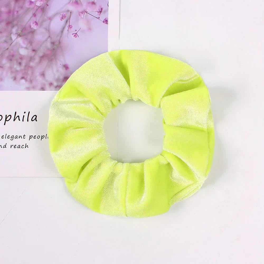A bright lime green velvet scrunchie is shown against a white background.