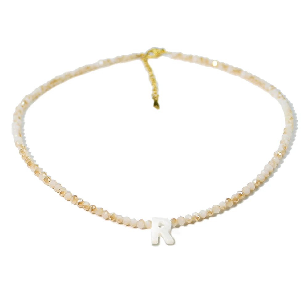 A delicate necklace made of mother of pearl beads with crystal accents, featuring an initial charm.