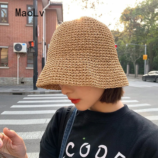 A person wearing a hand-woven straw visor hat outdoors.