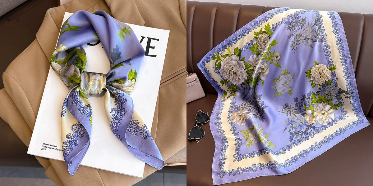 A purple floral print silk scarf draped on a light-colored card next to a brown leather sofa.