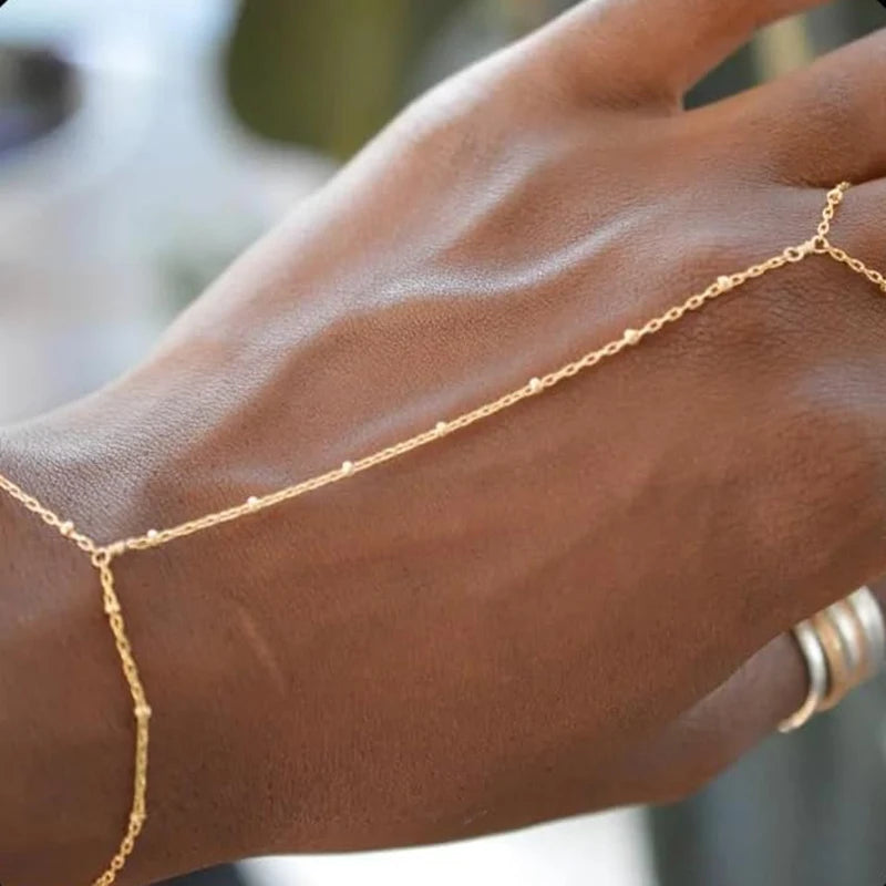 لقطة مقربة ليد ترتدي سوارًا خفيفًا من سلاسل ذهبية مطلية على المعصم.