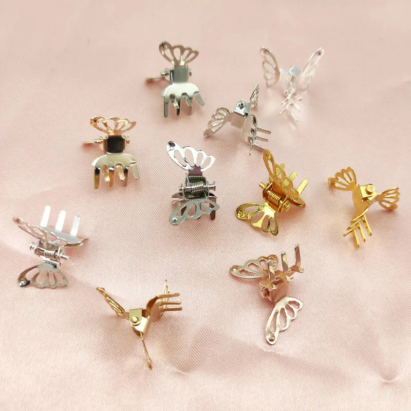 A collection of ten mini hollow butterfly metal hair clips in various gold and silver tones displayed on a pink background.