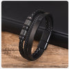 Schwarzes geflochtenes Lederarmband, das am Handgelenk getragen wird und auf einer Holzoberfläche liegt.