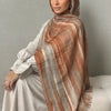 Una mujer vistiendo una elegante bufanda hijab a rayas naranja y beige con una blusa gris claro.