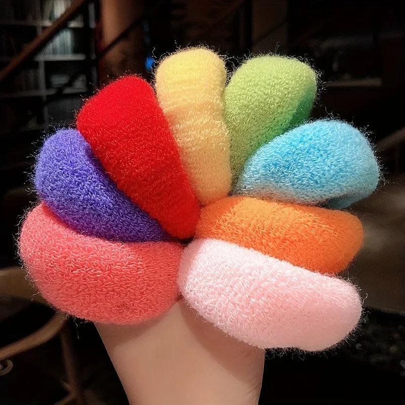 A collection of multi-colored cotton elastic hair ties in shades of red, orange, yellow, green, and purple are displayed on a