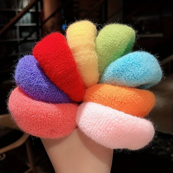 A collection of multi-colored cotton elastic hair ties in shades of red, orange, yellow, green, and purple are displayed on a