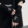 Black knitted fingerless gloves with white cross embroidery worn on a hand.