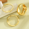 A set of three gold geometric wave bangles displayed on a light background.