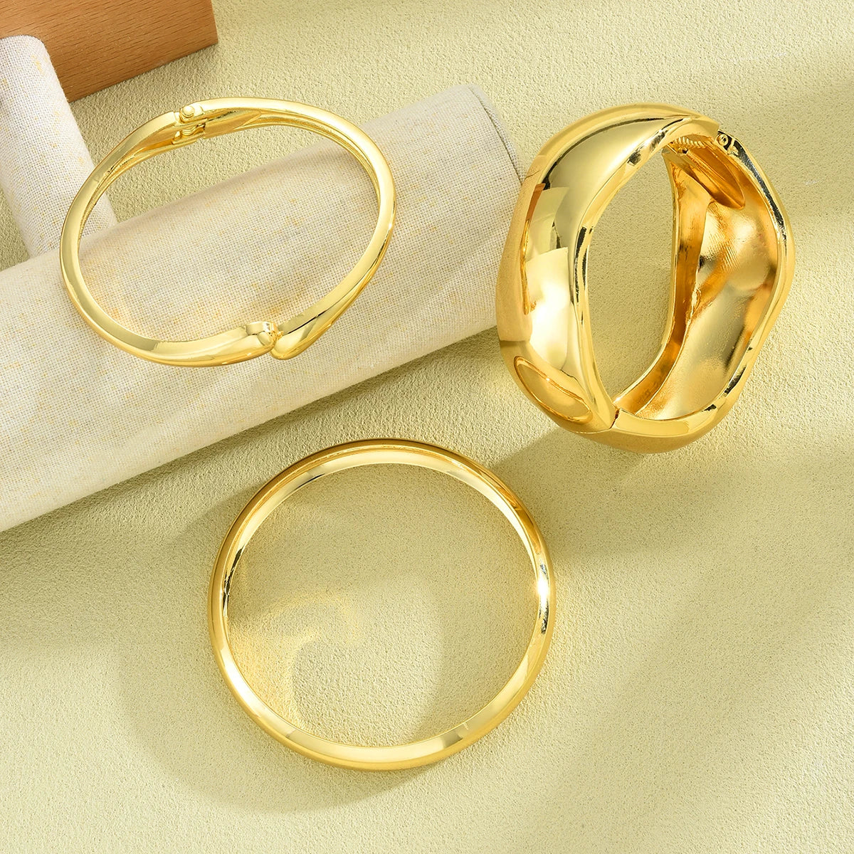 A set of three gold geometric wave bangles displayed on a light background.