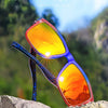 A pair of gradient square frame polarized sunglasses with vibrant orange and red lenses resting on a rocky surface.