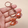 A hand holds a brown leather coffee keychain featuring a small heart-shaped cup and a miniature coffee pot.