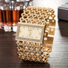 A gold stainless steel fashion quartz diamond watch with a detailed gold bracelet resting on a dark surface.