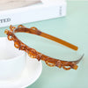 A close-up of an amber multi-layer braided hair headband clip resting on a white surface.