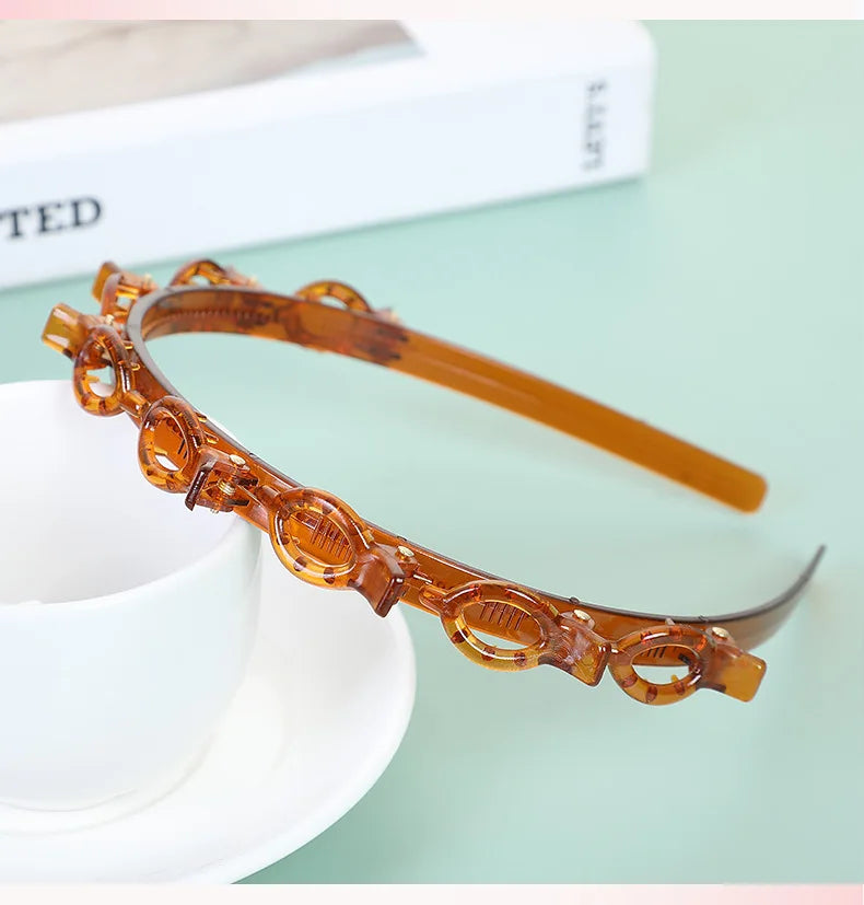 A close-up of an amber multi-layer braided hair headband clip resting on a white surface.