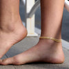 A close-up of a person's ankle wearing gold silver plated adjustable beaded anklets.