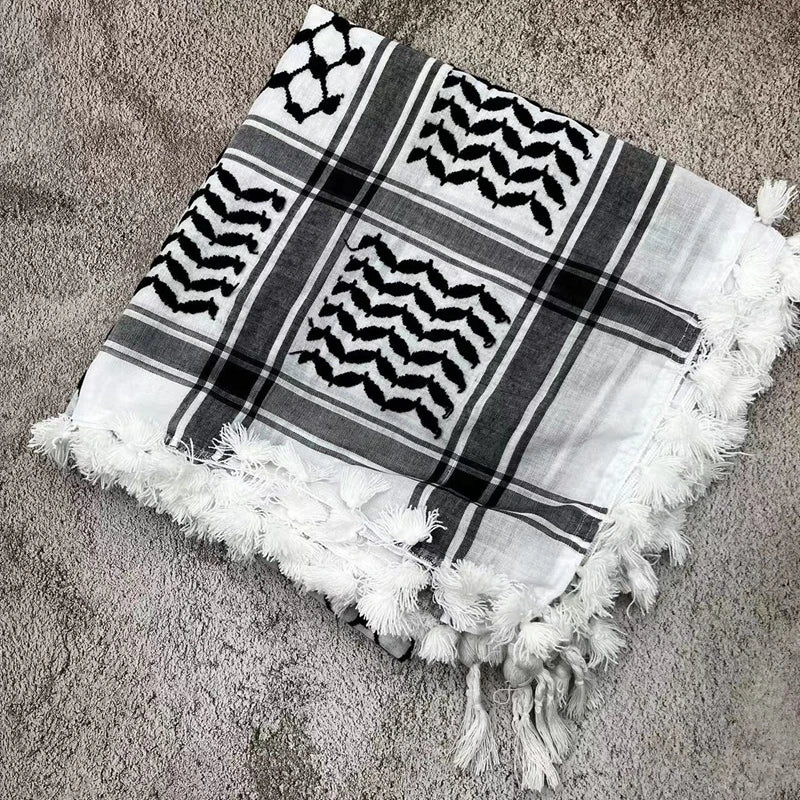 Pañuelo shemagh de algodón a cuadros con patrones geométricos en negro y gris y flecos blancos.