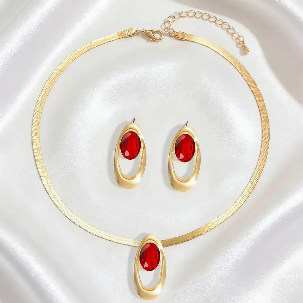 Gold necklace set featuring three oval red gemstone pendants and a gold chain.