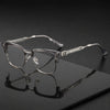 Une paire de lunettes vintage à demi-monture transparentes posée sur une surface sombre avec un reflet.