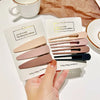 A hand holds a set of vintage frosted geometry hair clips in various shades and sizes displayed on a card.