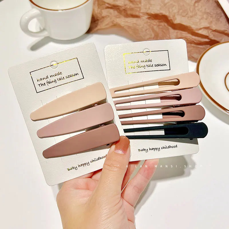 A hand holds a set of vintage frosted geometry hair clips in various shades and sizes displayed on a card.