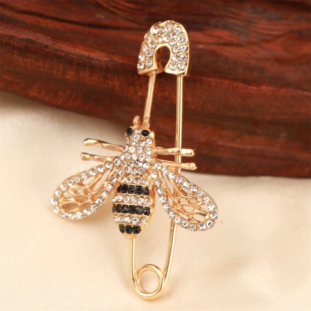 Broche ton or présentant une abeille et un insecte détaillés avec des pierres claires.