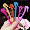 A hand holds several colorful hair elastic and rubber band remover tools in various shades of pink, orange, yellow, and blue.