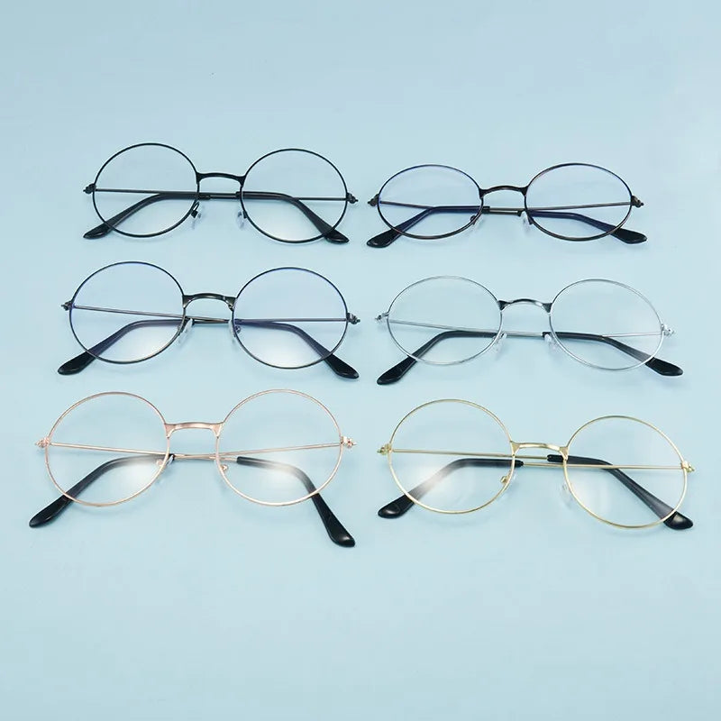 Colección de gafas redondas de metal en monturas negras y doradas sobre fondo azul claro.