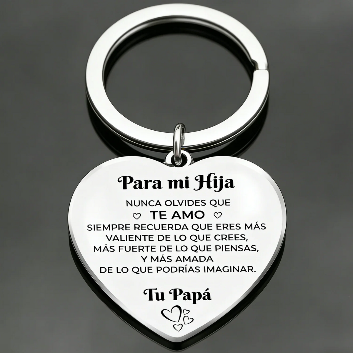 Llavero en forma de corazón plateado con texto grabado en español e inglés.
