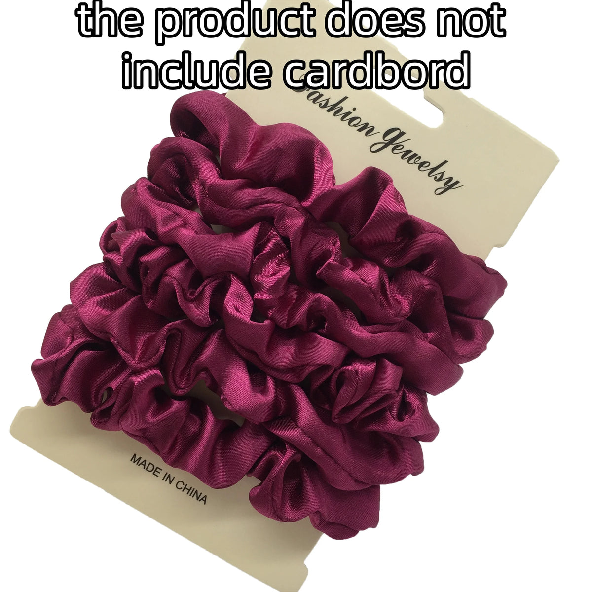 A pile of deep magenta satin hair scrunchies is shown on a cardboard background.
