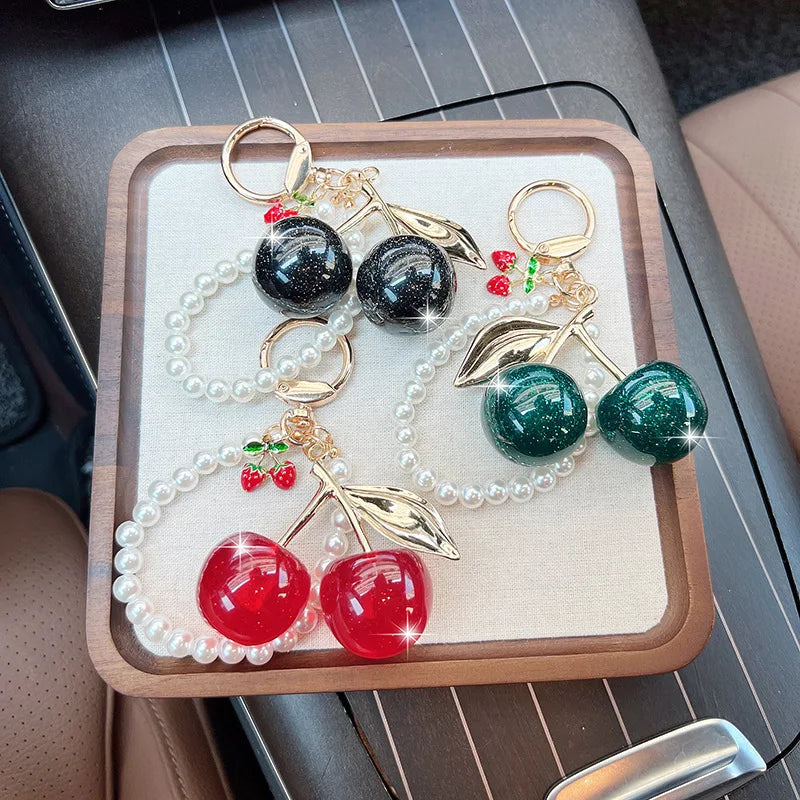 A display of sweet cherry pearl bead key chain decorations featuring red and green beads on white pearls.