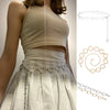 Un vestido beige con cinturón de cadena metálica de círculo y delicados collares de corazón.