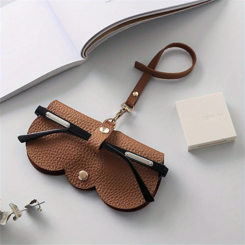 A brown PU leather pouch with a leather strap is shown next to a white box, used for eyewear storage.