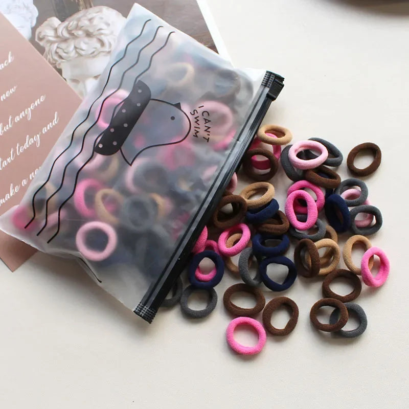 A clear plastic pouch filled with various colored elastic hair bands and rings.