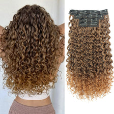 A close-up of long brown kinky curly hair extensions with a clip-in band.