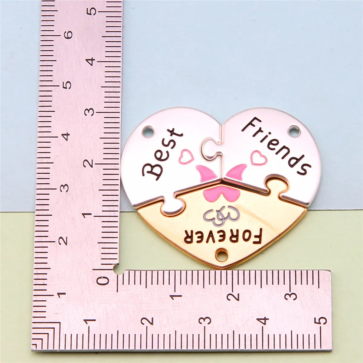 Dos colgantes de collar con forma de corazón para amistad, etiquetados como 'Mejores Amigos para Siempre', medidos contra una