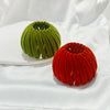 Two textured velvet hair clips in shades of green and red resting on a white surface.