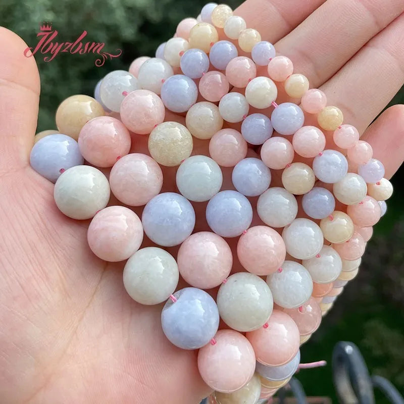 A hand holds a strand of smooth round jade beads in various pastel colors like pink, white, and blue.