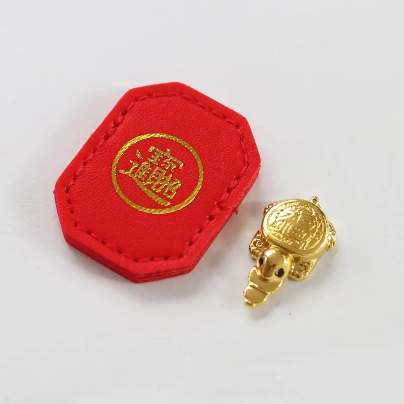 A red hexagonal tag with a gold circular emblem and a small gold turtle charm.