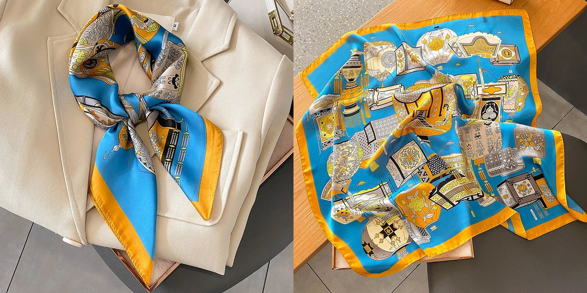 A vibrant blue silk scarf with a floral print and gold accents is displayed on a light background.