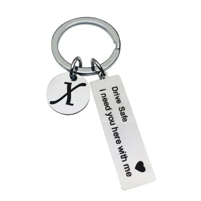 Silver keychain with an X charm and a tag that reads Drive Safe I need you here with me