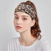 A woman wearing a leopard print fashion headband on her hair, against a light gray background.