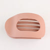 A light peach colored flat circular hair clip set with horizontal slits for hair.